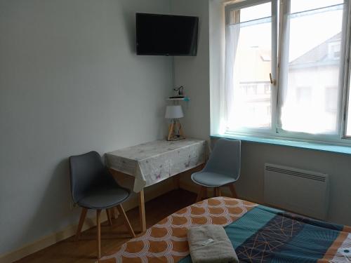 1 dormitorio con 2 sillas, escritorio y 1 cama en Appartement paisible - cœur de ville, en Le Creusot