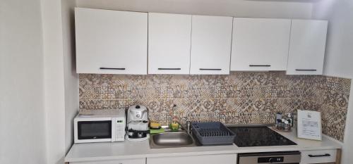 a kitchen with white cabinets and a sink and a microwave at Green Nest in Brezoi