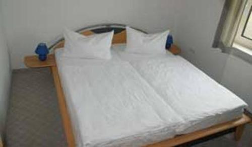 łóżko z białą pościelą i poduszkami w pokoju w obiekcie Landsitz Rügen w mieście Glowe