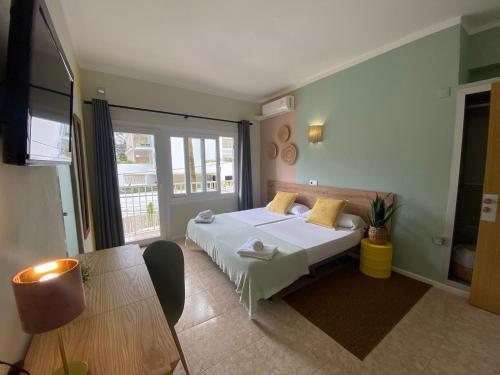 a bedroom with a white bed and a table at Hostal Playa de Palma in Playa de Palma