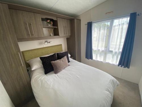 Un dormitorio con una cama blanca con almohadas y una ventana en Serenity Holiday Home, en Saint Osyth
