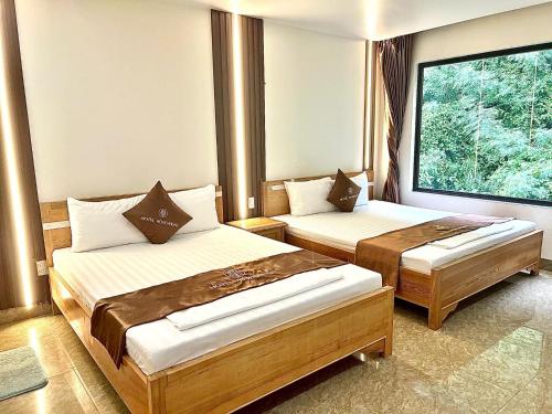 a hotel room with two beds and a window at Cat Ba Rose Nhung Hotel in Cat Ba