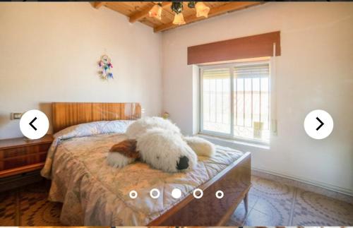 a teddy bear laying on a bed in a bedroom at LA VILLA in Villarrín de Campos