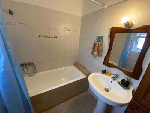 a bathroom with a sink and a tub and a toilet and a mirror at Anastasia's Apartment - Semi-basement Apartment (Rafaella Resort) in Kokóni