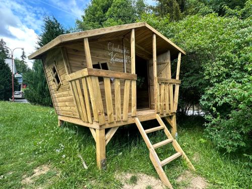 a wooden dog house with a ladder in the grass at Depandance hotelu Kamzík in Malá Morávka