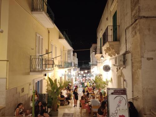 una multitud de personas caminando por una calle por la noche en Casetta nel centro storico, en Mattinata