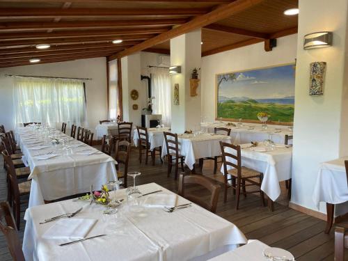 un comedor con mesas y sillas blancas y una pintura en Hotel Ristorante Le Querciolaie dei Ricci, en Fonteblanda