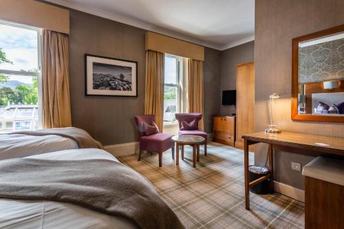 a hotel room with two beds and a desk at Auchrannie Resort in Brodick