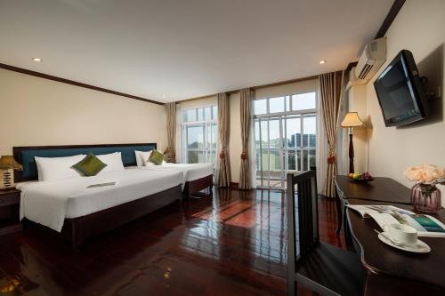 a hotel room with two beds and a television at Golden Sun Hotel in Vientiane
