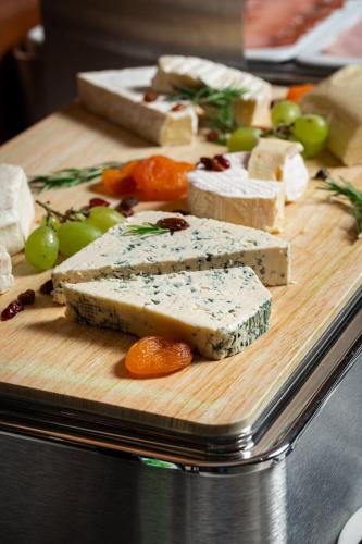 a wooden cutting board with different types of cheese and fruit at Hotel California by Aycon in Sveti Stefan