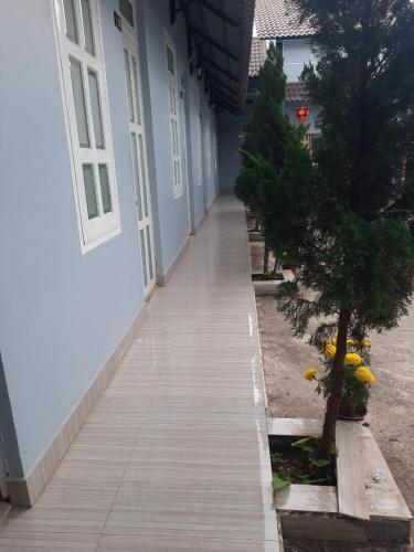 a wooden walkway next to a building with a tree at Motel Khánh Vy in Bao Loc