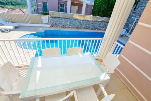 a white table and chairs on a balcony with a pool at Villa Rana The Royal Links Sarigerme in Ortaca