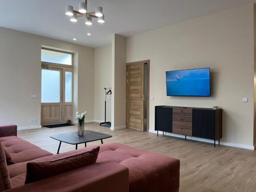 a living room with a couch and a flat screen tv at Viesu nams Pupa in Kuldīga
