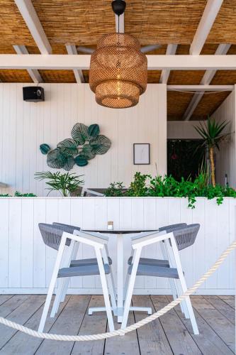a white table with two chairs and a light fixture at Hotel California by Aycon in Sveti Stefan