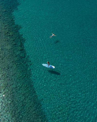 a person on a surfboard in the water at Hotel California by Aycon in Sveti Stefan