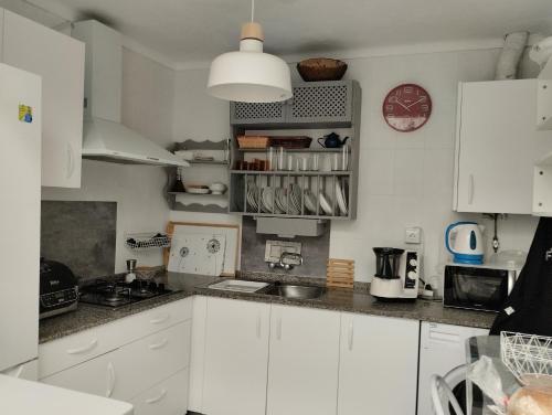 a kitchen with white cabinets and a clock on the wall at La casa de loto in Alcalá de los Gazules