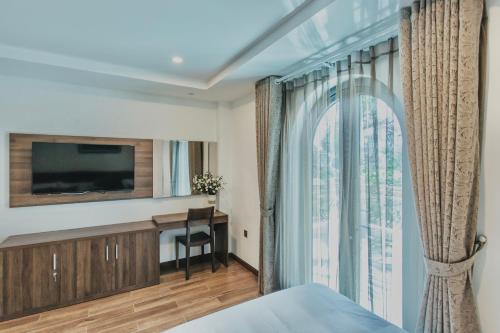a bedroom with a bed and a tv and a window at La Sera Suites Nha Trang in Nha Trang