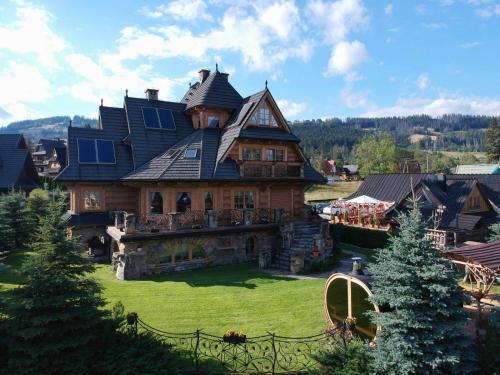 a large wooden house on a green yard with trees at Willa Tatrzański Zomecek in Kościelisko