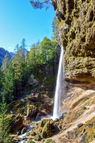a waterfall on the side of a mountain next to a river at Apartments Blažič in Kranjska Gora