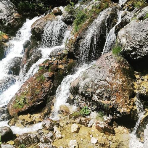 a waterfall on the side of a mountain with rocks at Apartments Blažič in Kranjska Gora