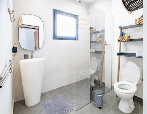 La salle de bains est pourvue de toilettes et d'une douche en verre. dans l'établissement Ô Ruisseau Lodge lodge Cocotier, à Saint-Louis