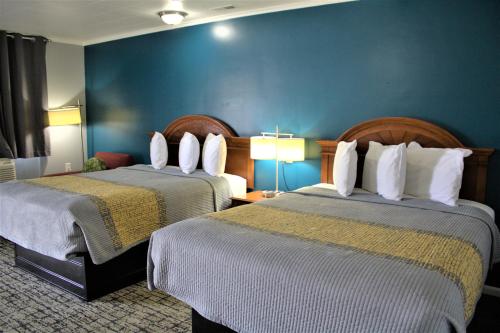 a hotel room with two beds and a blue wall at Campbell's Motel Scottsburg in Scottsburg