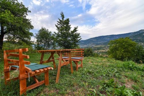 two benches and a table and a chair on a hill at Cozy barrel in Nikšić
