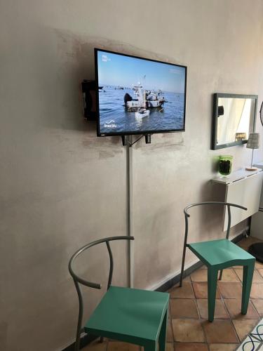 TV de pantalla plana en una pared con 2 sillas y mesa en Casa Marieta, en Sarzana