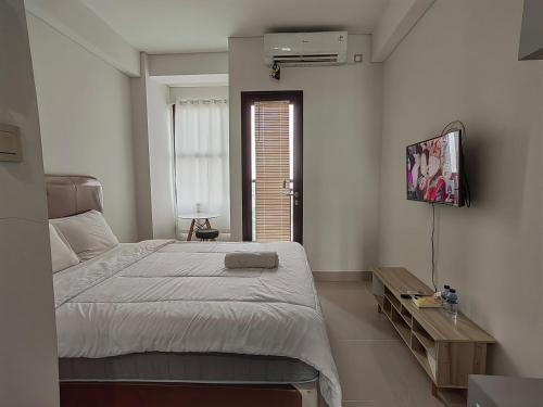 a bedroom with a bed and a flat screen tv at Transpark Cibubur By Arsakha Property Management in Kalimanggis