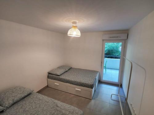een slaapkamer met 2 aparte bedden en een raam bij Magnifique appartement pour 8 personnes à Montpellier - WIFI/PARKING in Montpellier