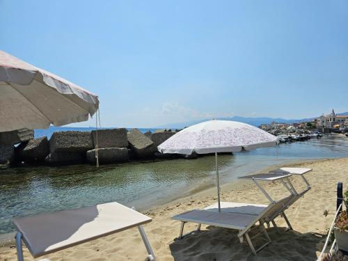 een paar stoelen en een parasol op een strand bij Casa di Nonna Mariella in Messina