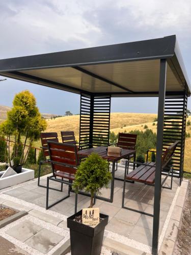 a pavilion with benches and a table and chairs at Wild nest Deer Lux in Zlatibor