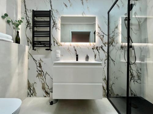 ein Badezimmer mit einem weißen Waschbecken und einem Spiegel in der Unterkunft Apartamenty Wolwowicz in Jelenia Góra