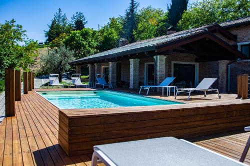 ein Pool auf einer Holzterrasse mit Stühlen in der Unterkunft Resort Villa Paola in Longiano