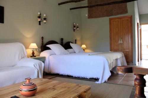 a bedroom with two beds with white sheets and a table at Chorros del Río Mundo in Riópar