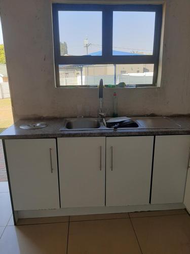 eine Küchentheke mit einem Waschbecken und einem Fenster in der Unterkunft Fumas guesthouse in Duvhapark