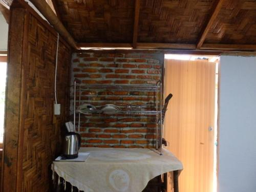 uma cozinha com uma mesa com uma parede de tijolos em Magpie homestay em Bukit Lawang