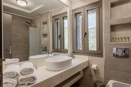 a bathroom with a sink and a large mirror at Dream Villas Stoupa in Stoupa