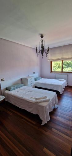um quarto com 2 camas e um lustre em Apartamento Malzapatu - 4 dormitorios - Llanes em Llanes