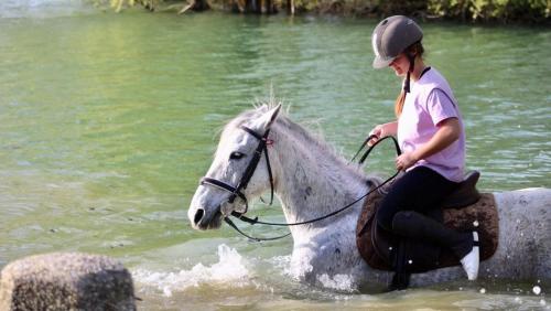 a girl riding a white horse in the water at RIVER PARADISE in Goyave