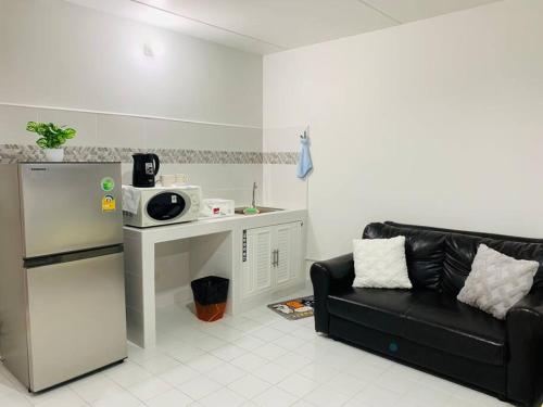 a living room with a black couch and a microwave at Condo popular T8 fl.12 in Thung Si Kan