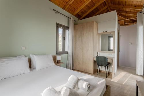 a bedroom with a large white bed and a desk at Dream Villas Stoupa in Stoupa