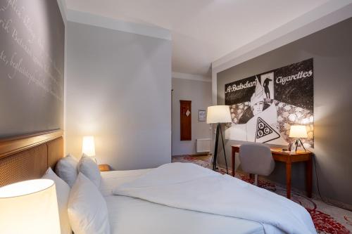 a hotel room with a bed and a desk with two lamps at Batschari Palais Baden-Baden in Baden-Baden
