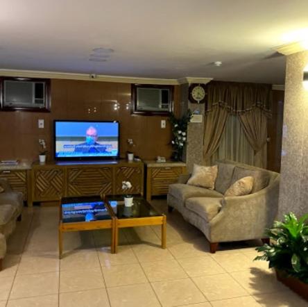 Jamjoom Hotel في جدة: غرفة معيشة مع أريكة وتلفزيون
