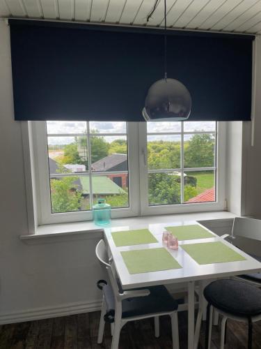 a dining room with a table and two windows at Overnatning tæt på Silkeborg in Engesvang