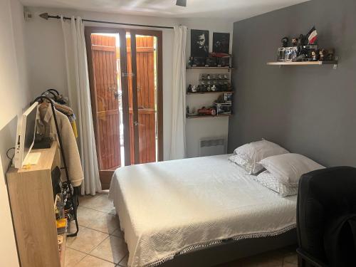 a bedroom with a bed and a television and a window at chez Guy in Marseille
