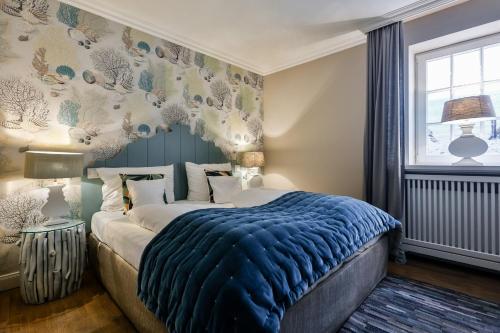 a bedroom with a bed with a blue blanket and a window at Strandvogtei Sylt in Rantum