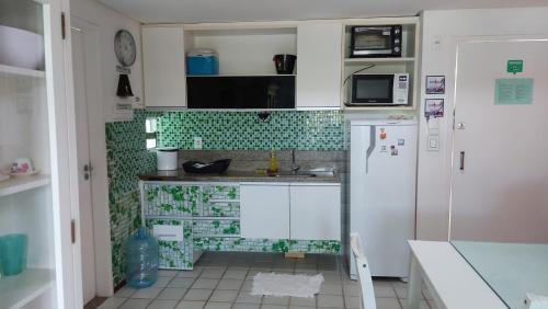 a small kitchen with green tiles on the wall at Ancorar Porto de Galinhas flat 7205 in Ipojuca