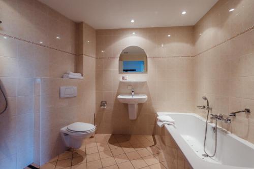 een badkamer met een bad, een toilet en een wastafel bij Appartementen Hotel Meyer in Bergen aan Zee