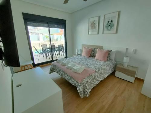 ein Schlafzimmer mit Bett und Fernseher und Balkon in der Unterkunft Villamolinos, villa con piscina privada. in San Pedro del Pinatar